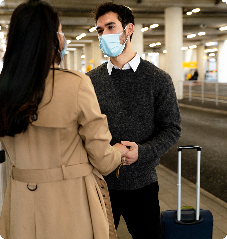 Travelers wearing face masks meeting at airport terminal with luggage