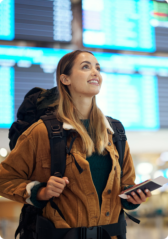 Female traveler with backpack holding passport at airport departure terminal